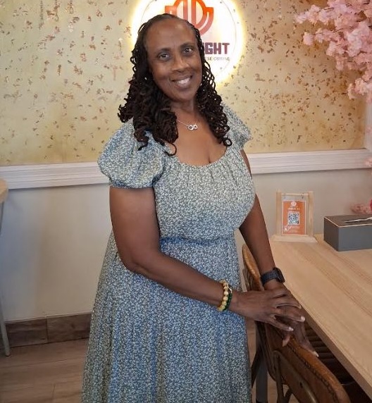 Mrs. Doretta C. Belale, CEO and Founder of OneLife OneSmile, smiling in front of pink blossoms